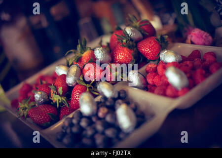 Une sélection de petits fruits à Pâques sur une table de salle à manger avec mini-oeufs de pâques répartis à. Banque D'Images