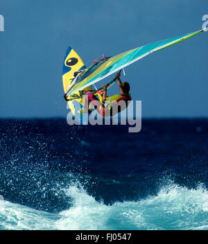 Sauter de joie . Windsurfer bondit à l'écart de la vagues contre un ciel bleu clair. Banque D'Images