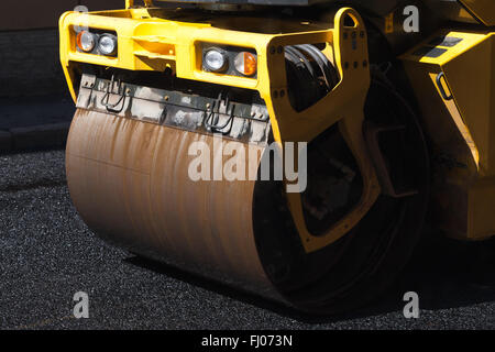 Fragment de rouleau jaune, urbains, routiers est en cours de construction, de l'asphaltage en cours Banque D'Images