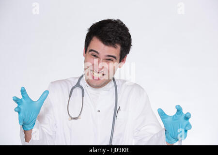 Jeune médecin homme portant des gants bleu, montrant visage fou Banque D'Images