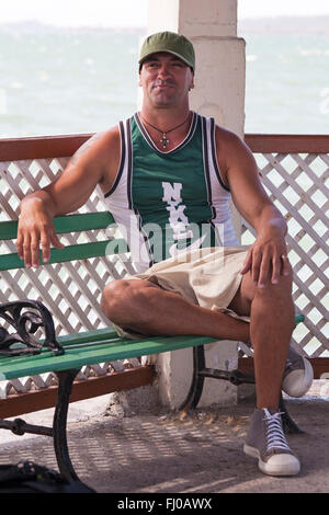 La vie quotidienne à Cuba Cuba - young man wearing Nike t-shirt assis sur un banc à Cienfuegos, Cuba en Mars Banque D'Images