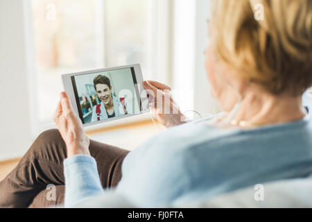 Senior woman looking at photo de jeune homme on digital tablet Banque D'Images