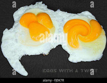 Œufs art alimentaire deux œufs de jaune d'oeuf triple friture avec une torsion artistique et une distorsion aux jaunes et à la surface antiadhésive.Super restaurant café image de la cuisine. Banque D'Images