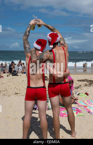 Men toasting un joyeux noël sur Coogee Beach, Sydney, New South Wales, Australia Banque D'Images