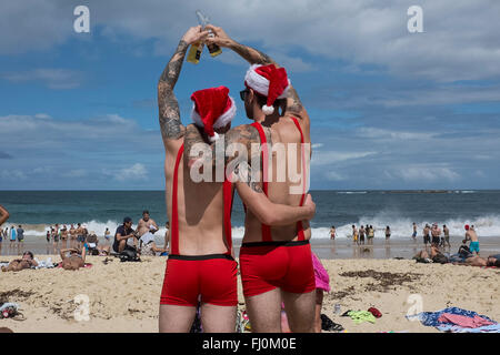 Men toasting un joyeux noël sur Coogee Beach, Sydney, New South Wales, Australia Banque D'Images