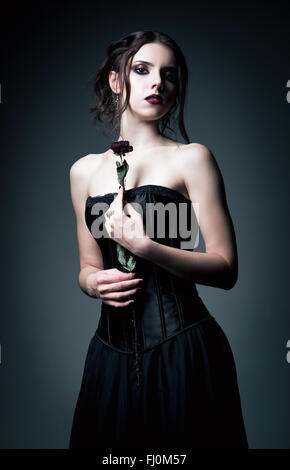 Portrait de belle fille goth tenant une fleur flétrie dans les mains Banque D'Images
