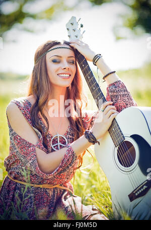 Portrait of a beautiful smiling woman with guitar hippie. Tourné en extérieur Banque D'Images