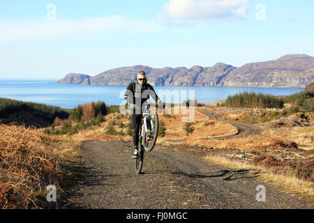 Isle of Mull, Scotland, UK. Feb 27, 2016. Man mountain biking dans le glorieux soleil du printemps sur le sentier de la Commission forestière Ardmore près de Tobermory. Credit : PictureScotland/Alamy Live News Banque D'Images