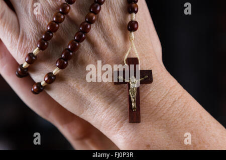 Close up of a woman's hands holding rosary a porté sur la croix Banque D'Images