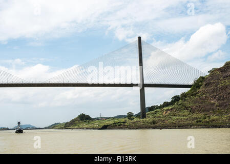 Pont Centennial Canal de Panama Ciudad de Panama Panama | CANAL DE PANAMA, Panama — Un bateau de pêche passe sous le Pont Centennial qui enjambe le Canal de Panama près des écluses de Pedro Miguel, sa silhouette à câbles tendus encadrée par une colline boisée. Achevé en 2004 pour marquer le centenaire de la République de Panama, le pont s'élève à environ 184 m (604 pi) et surplombe le canal de 80 m (262 pi) pour permettre aux navires Panamax de passer en dessous. Banque D'Images