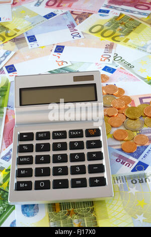 Calculatrice de poche avec écran blanc sur un arrière-plan constitué de pièces et billets en euros Banque D'Images