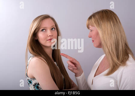 Adolescente d'être réprimandé par sa mère qui pointe vers un doigt à sa fille Banque D'Images