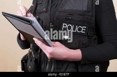 Agent de police portant gilet tactique à écrire des notes sur un bloc-notes Banque D'Images