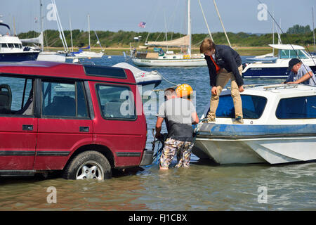 Bateau sur une remorque routière étant couplé à l'attelage de la voiture pour sortir de l'eau dans Chichester Harbour à Itchenor, Chichester, West Sussex, UK Banque D'Images