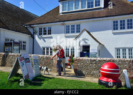 Couple walking with dog passant la capitainerie, la rue, Itchenor, Chichester Harbour, West Sussex, England, UK Banque D'Images