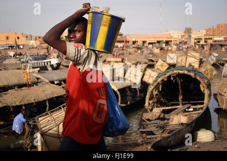 L'homme travailleur portant un seau en plastique avec des marchandises au port de Mopti au Mali, Afrique de l'Ouest Banque D'Images
