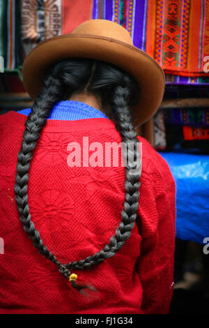 Femme péruvienne avec chapeau melon et tresses en marché Pisac Banque D'Images