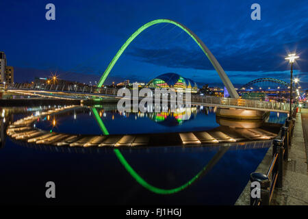 Une vue de la nuit de Gateshead Millennium Bridge reflétée dans la rivière Tyne avec le sage gateshead & le Tyne Bridge en arrière-plan Banque D'Images