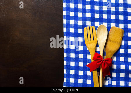 Table en bois avec vérifié cirée et des ustensiles de cuisine en bois avec ruban rouge Banque D'Images