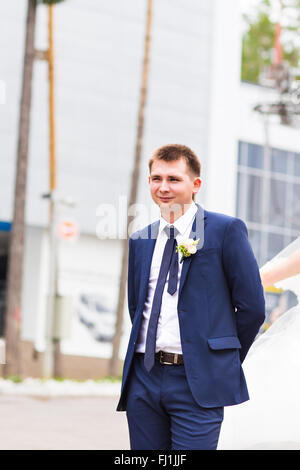 Beau palefrenier à tuxedo mariage souriant et en attente d'épouse. Happy smiling young groom. Riche mariés à jour du mariage. Marié en costume élégant smoking. Handsome young man in tuxedo. Banque D'Images