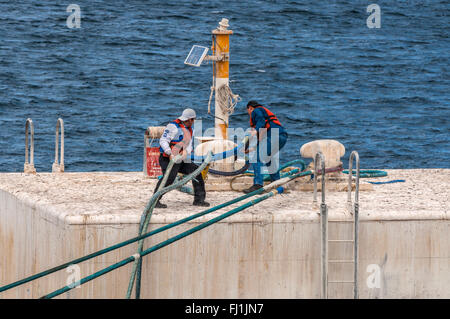Sur la plate-forme d'un jette son travailleurs l'amarrage d'un navire en câble Harbour Banque D'Images