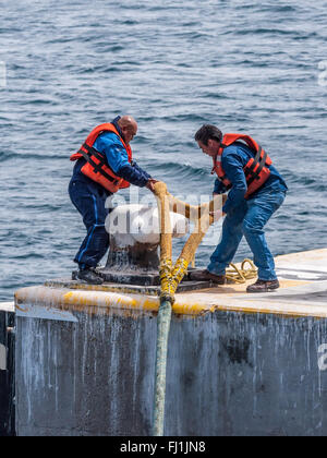 Sur la plate-forme d'un jette son travailleurs l'amarrage d'un navire en câble Harbour Banque D'Images