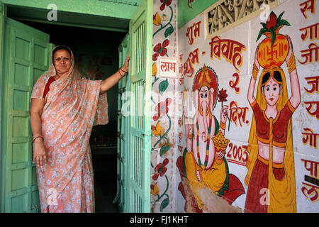 Femme opeing la porte de sa maison à Jaisalmer, Rajasthan, India Banque D'Images