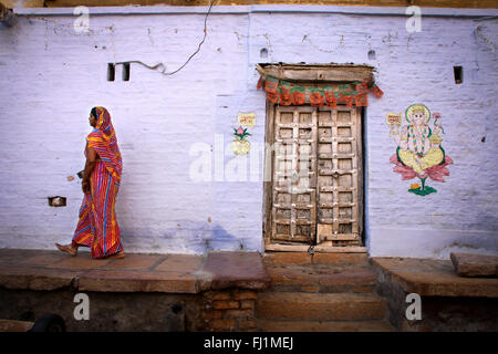 Femme marche à l'intérieur de fort Jaisalmer, en face d'une maison avec Le Dieu Ganesh peinture, Rajasthan, Inde Banque D'Images