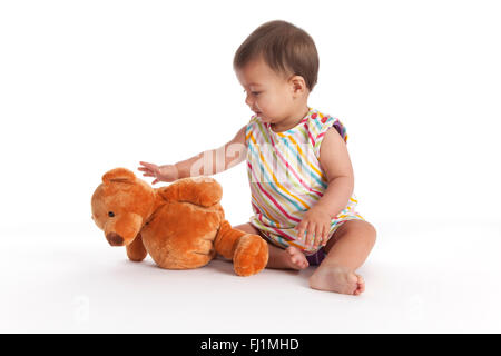 Baby Girl atteindre pour son ours en peluche sur fond blanc Banque D'Images