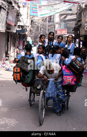 L'homme travaillant dur pour amener les enfants indiens à l'école le matin à Delhi Banque D'Images