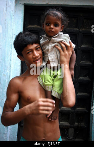 Les jeunes monter guy porte son frère sur son épaule, le port de kohl sur ses yeux , Varanasi , Inde Banque D'Images