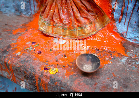 Close up sur les poudres de couleur rouge avec de l'eau pour miwed puja sur statue en Varanasi , Inde Banque D'Images
