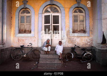 Deux hommes assis à l'entrée d'une maison à Jamnagar, Gujarat, Inde Banque D'Images