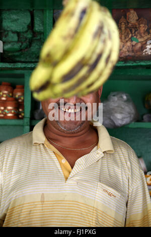 Smiling Indian man avec moustache cachée derrière une banane dans Kolkata Banque D'Images