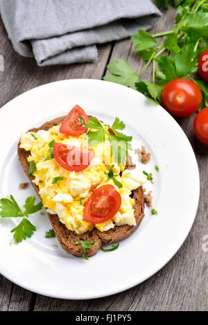 Le petit-déjeuner avec des œufs brouillés et des légumes frais sur du pain Banque D'Images