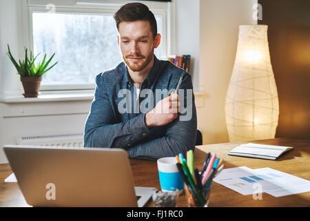 Satisfait man à la recherche à un ordinateur tout en souriant doucement Banque D'Images