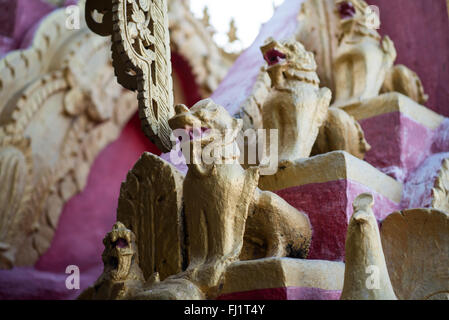 Figurines du lion gardien de la pagode Kuthodaw Mandalay Myanmar // MANDALAY, Myanmar — des détails décoratifs ornés et de petites figurines de lion gardien ornent les éléments architecturaux de la pagode Kuthodaw, mettant en valeur l'artisanat artistique bouddhiste birman traditionnel. Le complexe du temple, construit par le roi Mindon en 1857, abrite ce qui est largement connu comme le « plus grand livre du monde » composé de 729 stèles en marbre inscrites avec le canon Pali complet du bouddhisme Theravada. Ces sculptures complexes et éléments sculpturaux reflètent le style artistique traditionnel employé dans tout le parc de la pagode. Le complexe sert Banque D'Images
