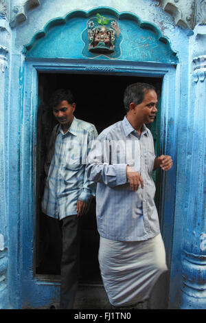 Les hommes de sortir d'une maison à l'architecture traditionnelle et porte , Varanasi, Inde Banque D'Images