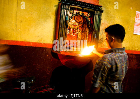 L'homme hindou priant dans le temple dans une rue étroite de Varanasi, Inde Banque D'Images