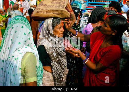 Les femmes exprimer tilak bénédiction sur le front d'un vieux Pèlerin en ghat de Varanasi , Inde Banque D'Images