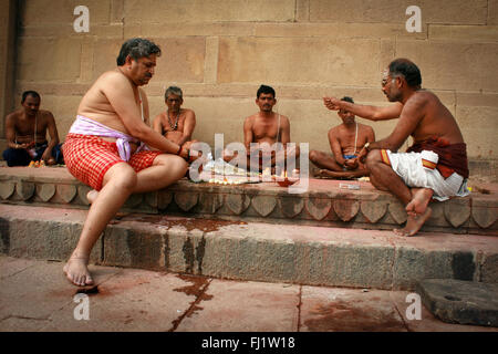 Pèlerins hindous priant avec le brahmane sur un ghat de Varanasi, Inde Banque D'Images