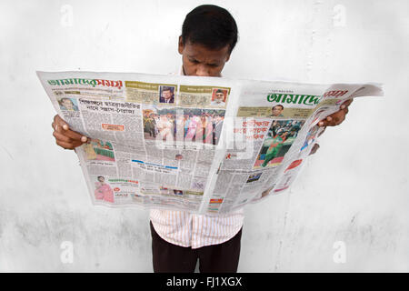 L'homme lit journal en langue bengali , Dhaka, Bangladesh Banque D'Images