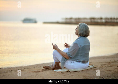 Mature Woman sitting on beach Banque D'Images