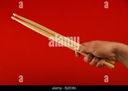 Man main tenant deux baguettes en bois sur fond rouge, diagonale, Close up Banque D'Images