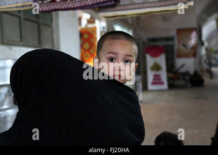 Portrait d'un jeune enfant dans le marché de Yazd, la tête couverte de mère (hijab) , Iran Banque D'Images