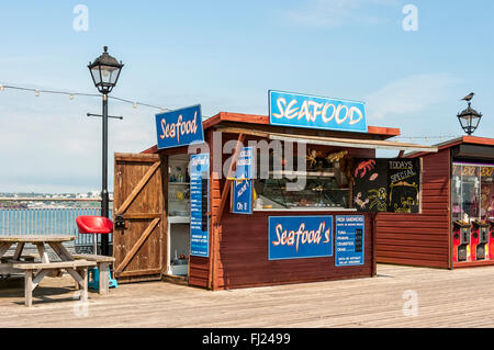 Plein soleil met l'accent sur la publicité sur les conseils scolaires à l'extérieur d'un décrochage en vendant des fruits de mer situé sur la jetée de Paignton Banque D'Images