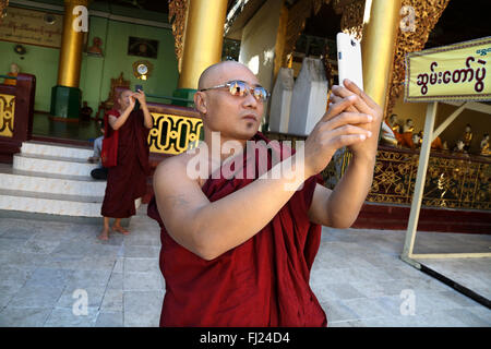 Le moine bouddhiste en tenant avec selfies je téléphone dans la pagode Shwedagon, Rangoon, Myanmar Banque D'Images