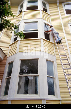 Peintre professionnel sur l'échelle la peinture maison historique, Charleston, Caroline du Sud, USA Banque D'Images