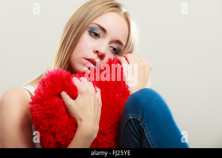 Broken Heart Love concept. Triste Malheureux woman hugging red heart pillow closeup Banque D'Images