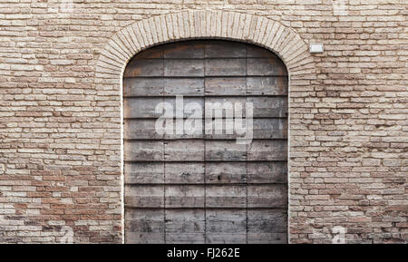 Porte en bois gris foncé avec arch dans le vieux mur de brique, la texture de fond photo Banque D'Images